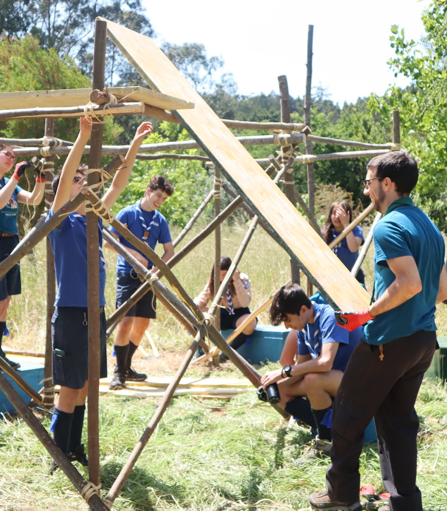 Escuteiros constroem uma estrutura de madeira num acampamento ao ar livre